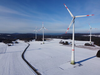 Aerial view of a wind farm in a winter landscape during sunset. Aerial view of wind turbines during...