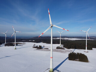 Aerial view of a wind farm in a winter landscape during sunset. Aerial view of wind turbines during...