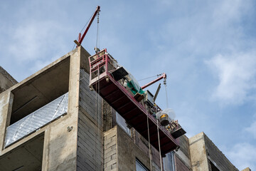 Construction cradle hanging at the wall of a house under construction