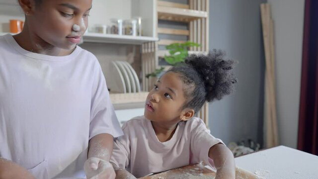 Happy child black skin thresh flour with rolling pin in kitchen