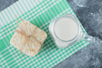 Delicious square crispbread and bottle of milk on marble background