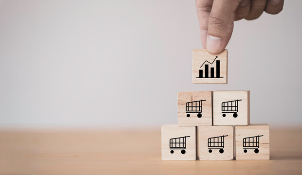 Business sale growth and expand shop franchise concept, Hand putting wooden cube block which print screen chart and shopping trolley cart on table. - Powered by Adobe
