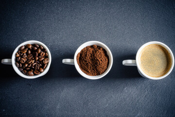 Obraz na płótnie Canvas 3 Tassen mit Kaffeebohnen, Kaffeepulver, Kaffee auf einer Schiefertafel