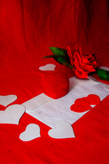 red rose on a red background with a ring box and hearts