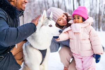 mixed race family in threesome spending new year holidays in park with their husky dog
