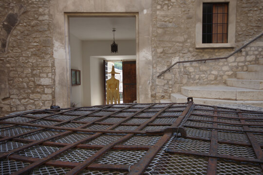 Detail of the grate of the ancient fifteenth-century well located in the courtyard of the Piccolomini Castle in Capestrano in Abruzzo, with a copy of the famous warrior in the background.