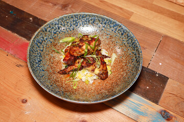 A plate of delicious honey chicken wings `on a wooden kitchen work top, restaurant style gourmet food