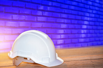 White hard safety helmet hat for safety project of workman as engineer or worker on wooden floor and brick wall background.