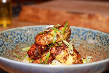 A plate of delicious honey chicken wings `on a wooden kitchen work top, restaurant style gourmet food