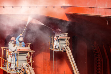 High pressure water jet to cleaning in cargo hold of cargo ship befor sahdblasting and plainting during ship repair in shipyard, and wear equipment protective safety bell for worker high.