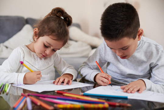 Beautiful children drawing pictures with color pencils at home