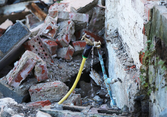 A  close up view of a leaking tap on a building site in Wales with builders rubble and discarded bricks.
