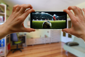 Watching football game at home via smartphone. Broadcasting soccer from the stadium.