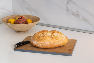 Fresh loaf of bread on kitchen cutting board.