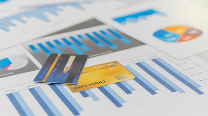 Two credit cards are placed on the graph document. The business is on the desk in the office