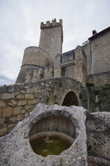 Fototapeta na wymiar Capestrano - Abruzzo - Entrance to the courtyard of the ancient medieval castle, with the original tower and defensive walls. In the background part of the small village.
