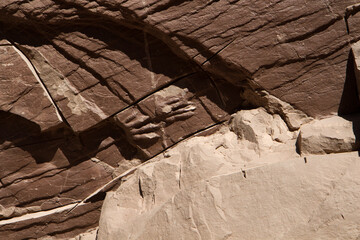 Prehistoric remains. Closeup view of ancient dinosaur fossilized foot print in the brown rock wall. 