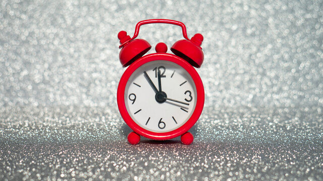 The red evening clock shows five minutes to midnight on a silver glitter background.