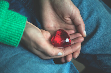 Red glass heart in woman hands
