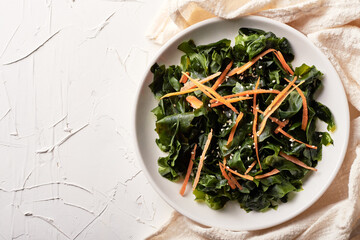top view homemade seaweed salad or kelp in white dish on white table background © boommaval
