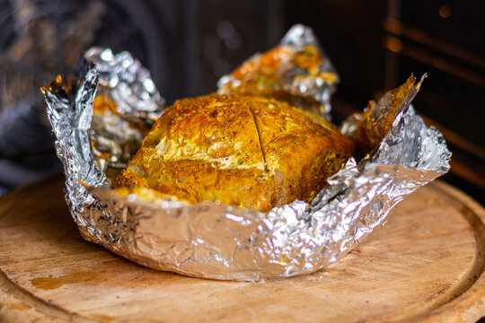 Baked piece of meat with spices in foil in the oven.