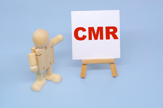 A wooden figure of a man points to the inscription CMR. Business Concepts