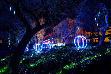 parque de noche con bolas de luces led iluminadas con un palacio detras 