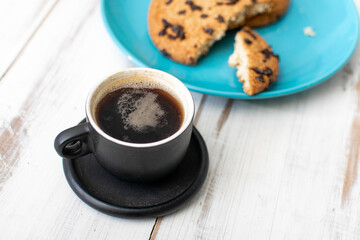 A cup of coffee and cookies with chocolate.