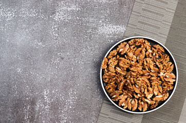 Walnuts on a round plate on a dark background. Top view, flat lay