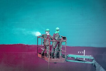 Worker in dry dock with water jet ship washing from sea vegetation and mussel colonies  during...