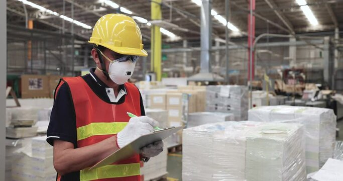 Warehouse workers hold clipboards while inspecting products before shipment.