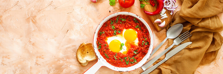 Breakfast. Fried eggs with vegetables - shakshuka in a frying pan or skillet. Typical food in Israel. Flat lay. Top view. Banner