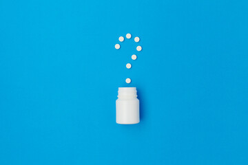 flat lay with pills and question mark on blue