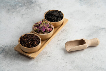 Wooden bowls with dried roses and infusion on a wooden board