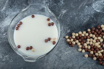 Bowl of fresh milk with chocolate balls on marble background