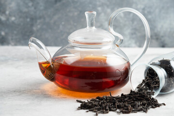 Dry tea leaves with teapot on a marble background
