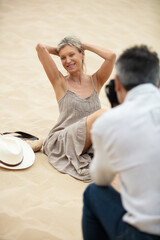 man clicking photo of woman with digital camera at beach