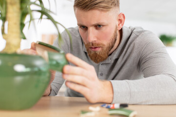 man repairing flower pot with glue