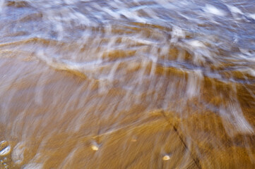 Waves on the seashore captured with a slow shutter speed. Natural abstract motion background.