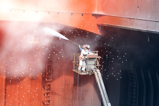 High pressure water jet to cleaning with Old ship washing  on Trucks have sherry piker, worker wear equipment protective safety harness and PPE in cargo hold of cargoship.