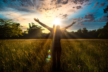 Young girl spreading hands with joy and inspiration facing the sun,sun greeting,freedom concept,...