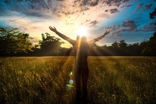 Young girl spreading hands with joy and inspiration facing the sun,sun greeting,freedom concept, nature lover ,spirit of forest