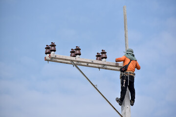 Worker on the high wear safety harness on the electric pole on blue sky fore safety concept,
