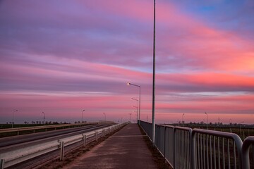 sunset over the bridge. street lights against the pink sky