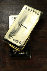 three 1 kg gold ingots on wooden background