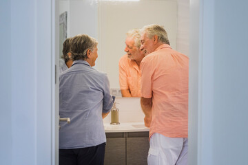 Obraz premium Real life for senior mature couple at home washing hand in the bathroom - hygiene concept for retired people