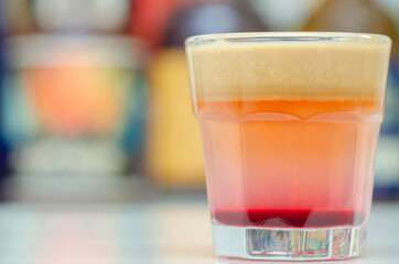 A colorful layered drink shot on a bar prepared by Bartender