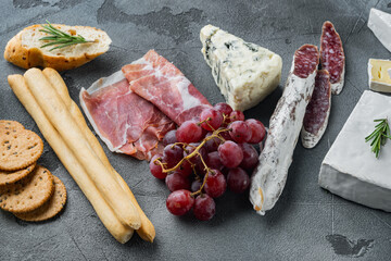 Assortment of cheese and meat appetizers, on gray background