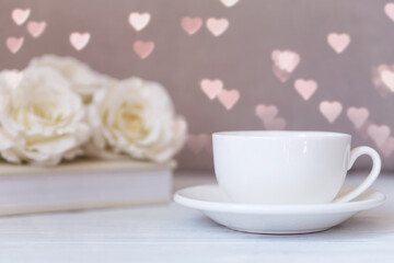 Fototapeta na wymiar Valentines day coffee mug, cup on the wooden table and heart bokeh background with roses