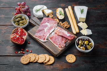 Appetizers table with differents antipasti, on dark wooden background